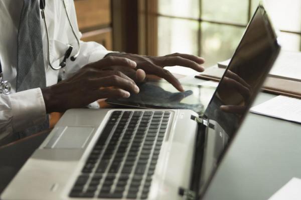 Hands working on a tablet next to a laptop