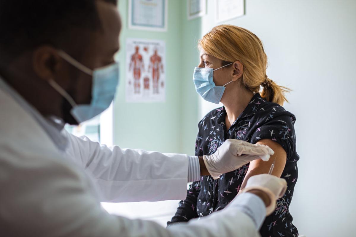 Doctor administering a shot to a patient, both of them wearing face masks