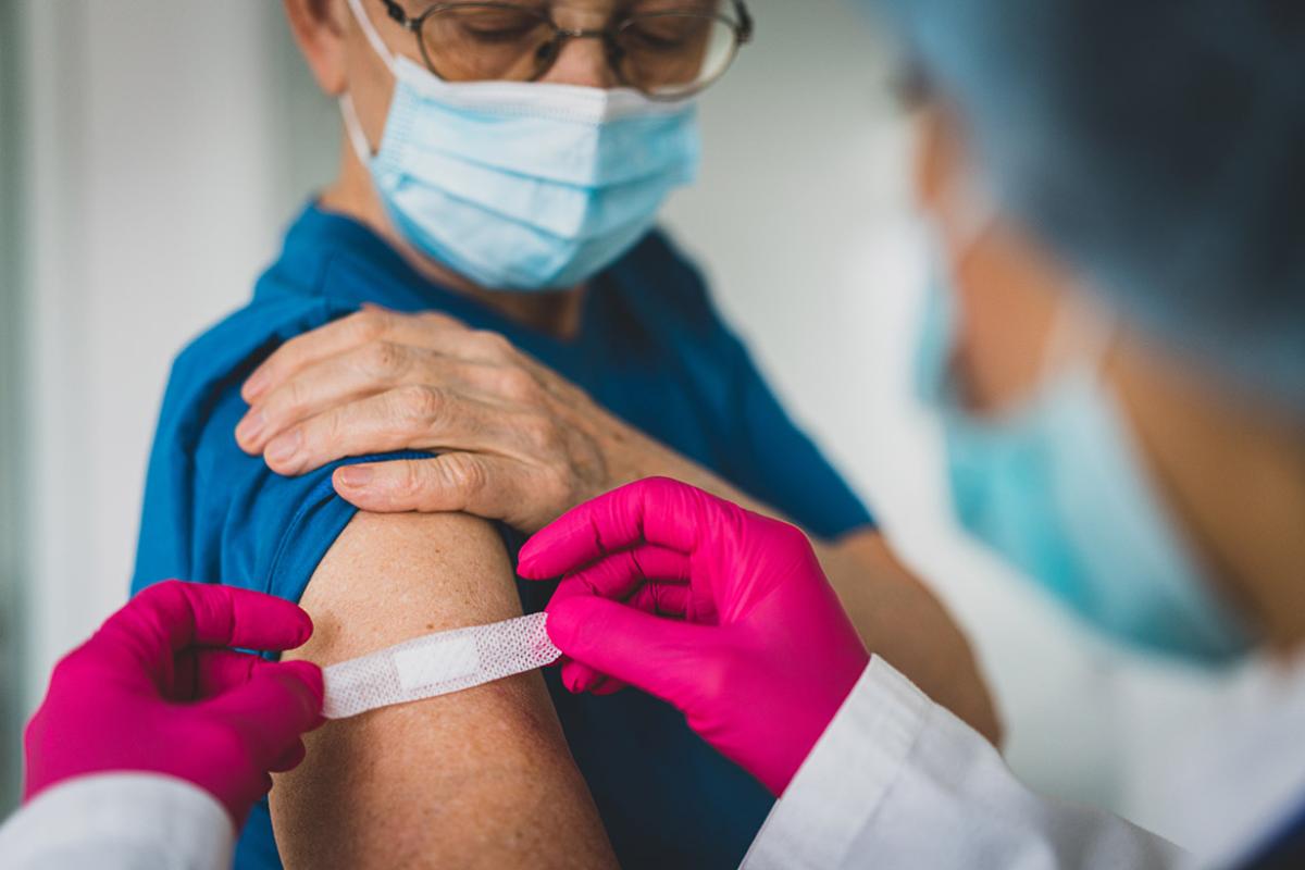 Person rolling up T-shirt sleeve to get a vaccine from a health professional