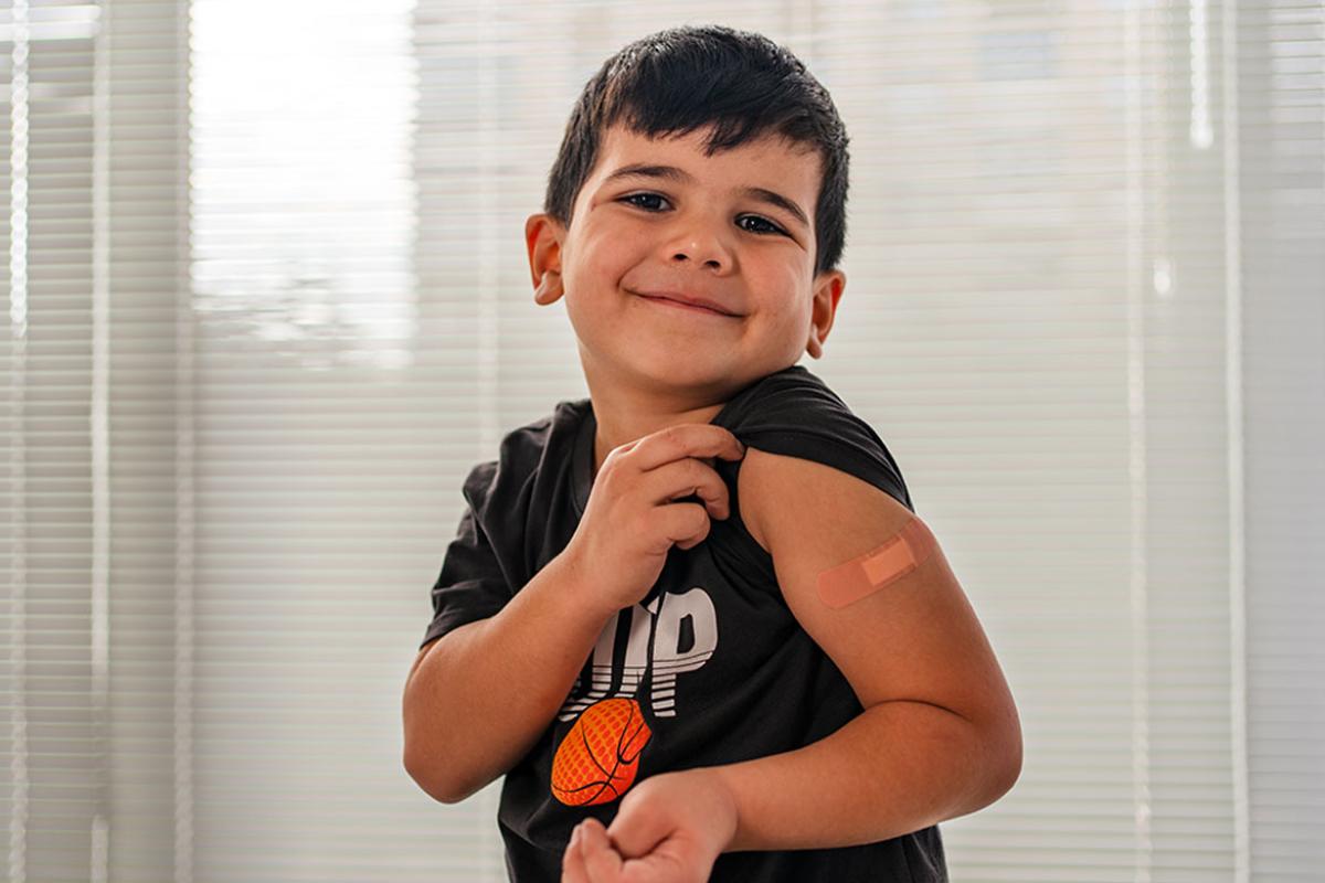 Smiling young child showing off bandage on arm