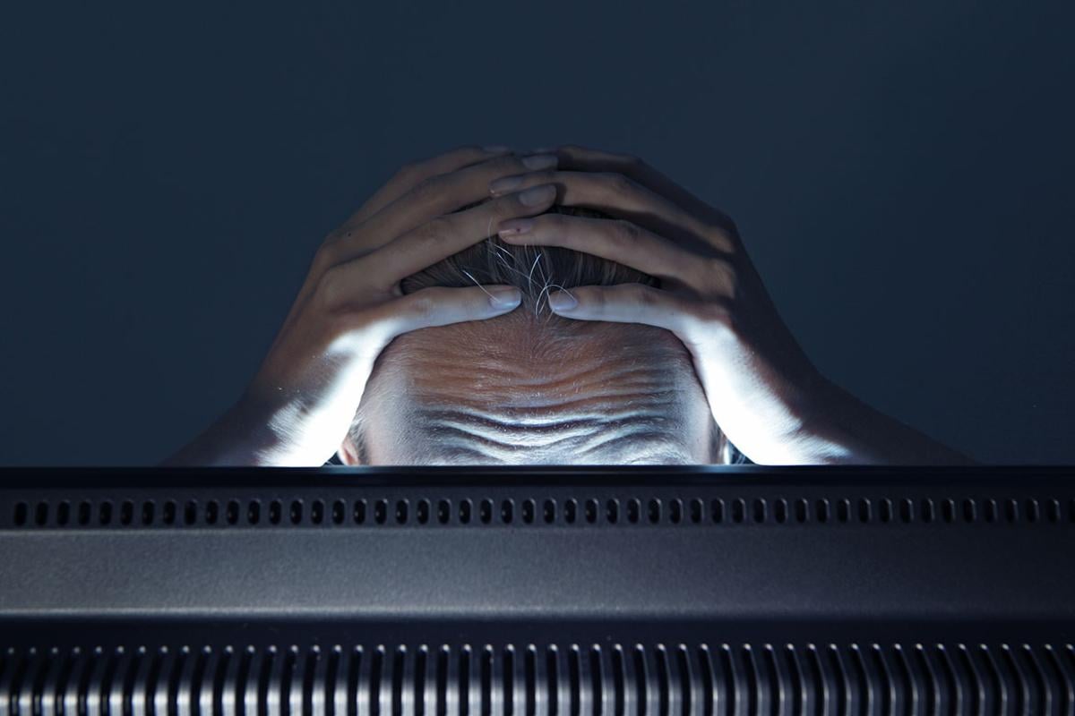 Person in front of a monitor with hands on head