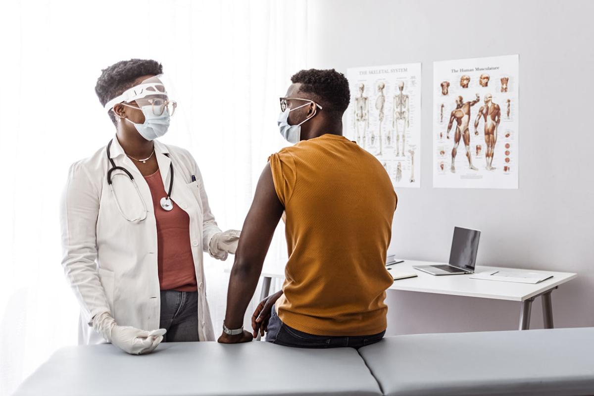 Physician vaccinating patient, both wearing masks