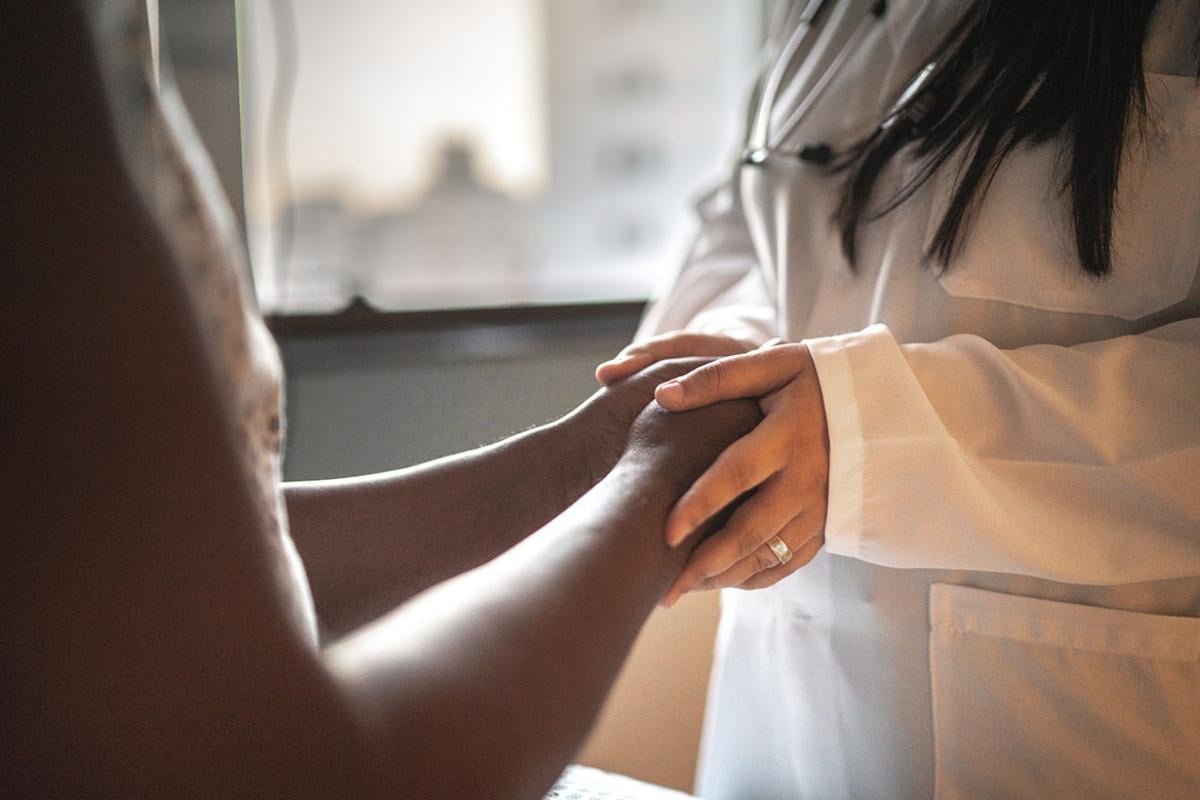 Female physician holding hands of patient