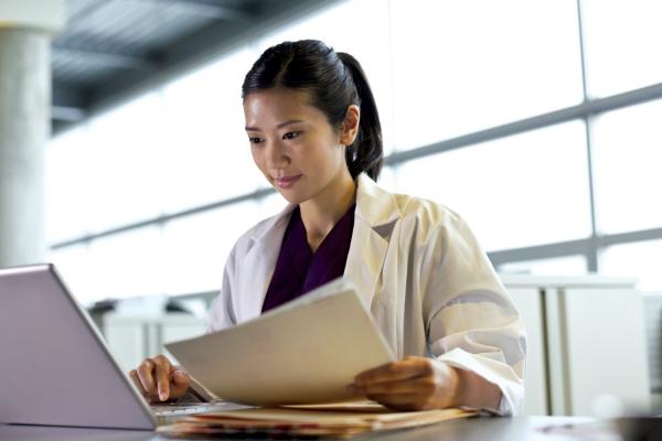 A resident reviews written notes and uses her laptop to consider her practice options after residency.